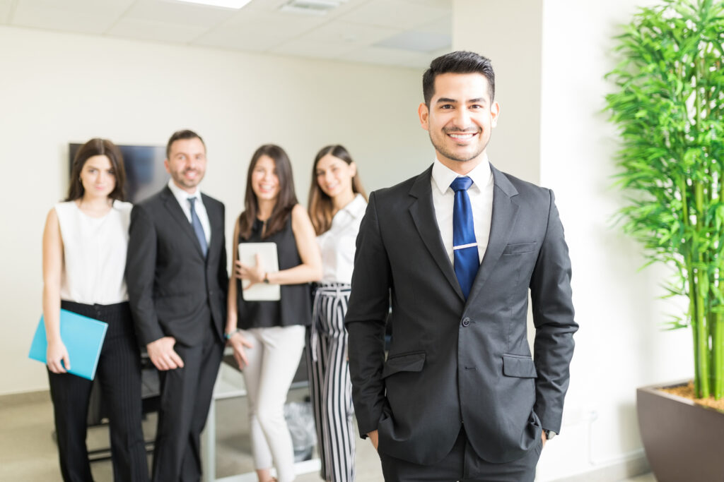 A man standing in front of co-workers in a real estate office.