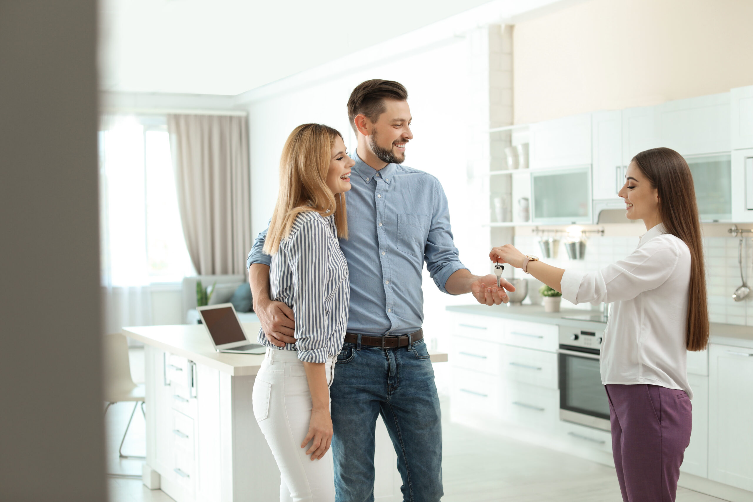 New homeowners accepting house keys from their agent who will receive a real estate referral fee from the referring agent.